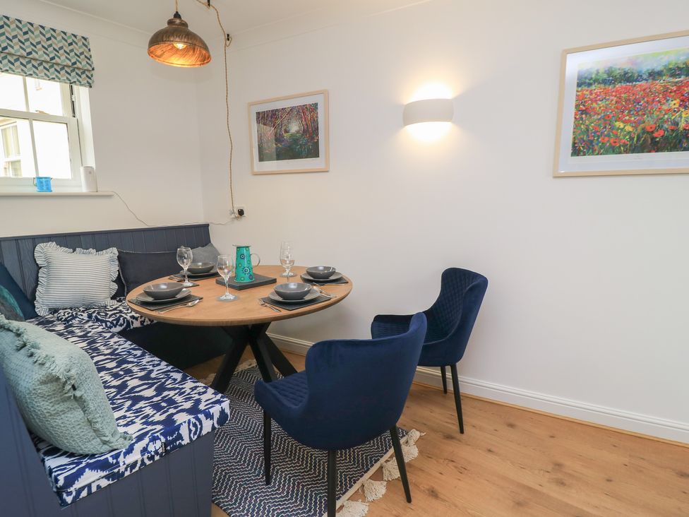 A dining room with a round table and seating at Weyside in Weymouth