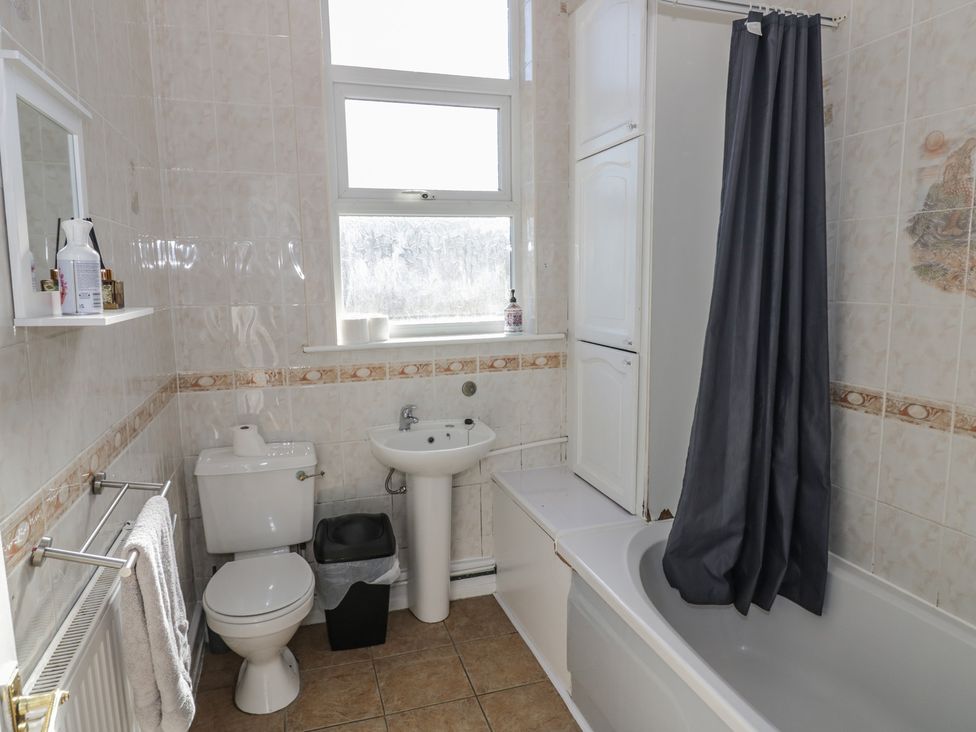 A bathroom with a bathtub, toilet, sink, and mirror at Cosy Escape in Birmingham