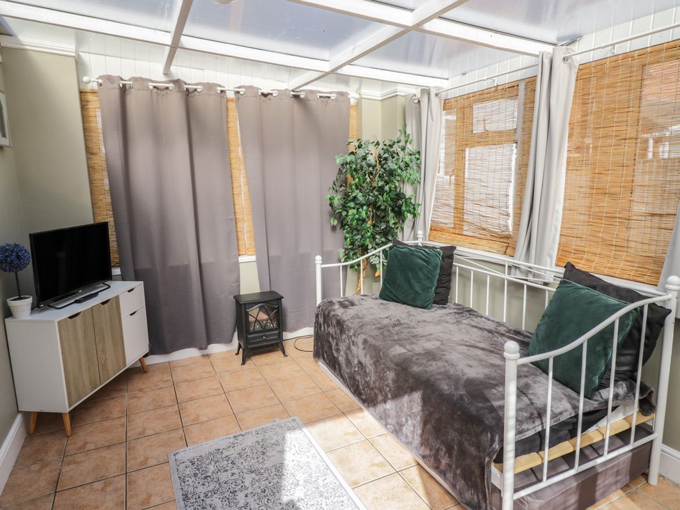 A conservatory with a sofa bed and television at Cosy Escape in Birmingham