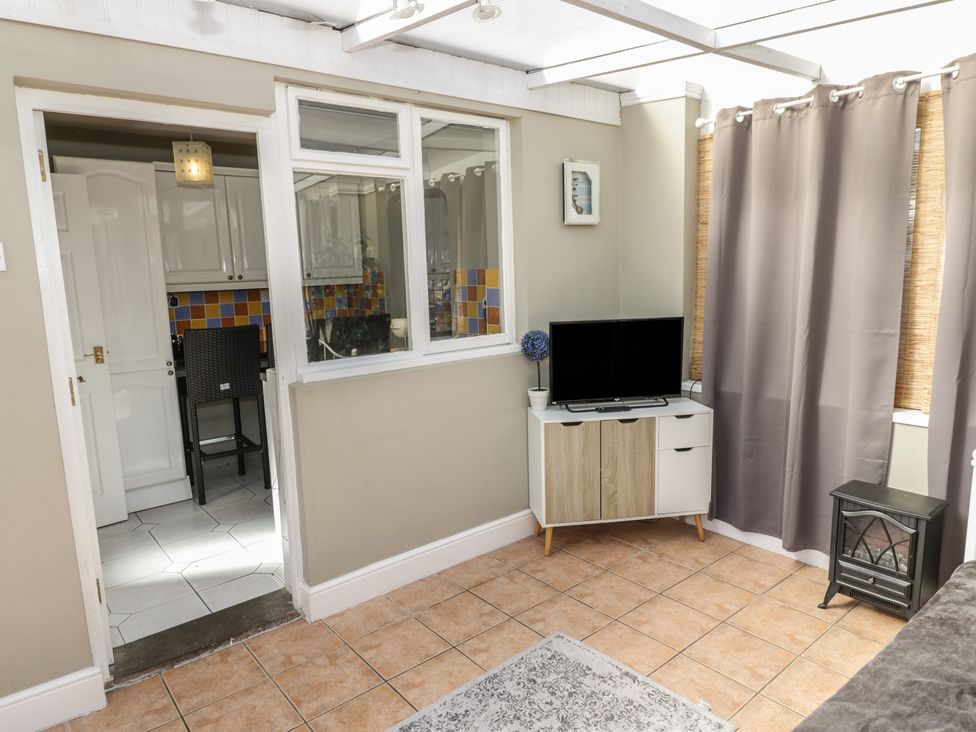 A conservatory with a tv and cabinets at Cosy Escape in Birmingham