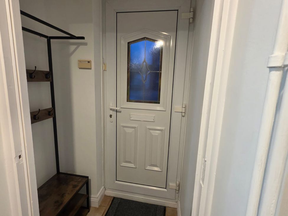 A hallway with a coat rack and a door at 12 Gorse Lane in Leicester