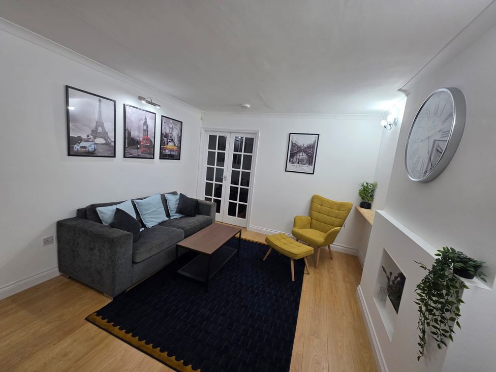 A living room with a sofa and yellow chair at 12 Gorse Lane Leicester