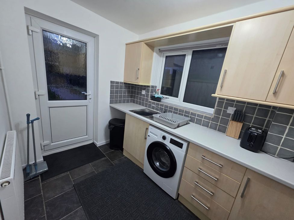A kitchen with a washing machine and sink at 12 Gorse Lane in Leicester