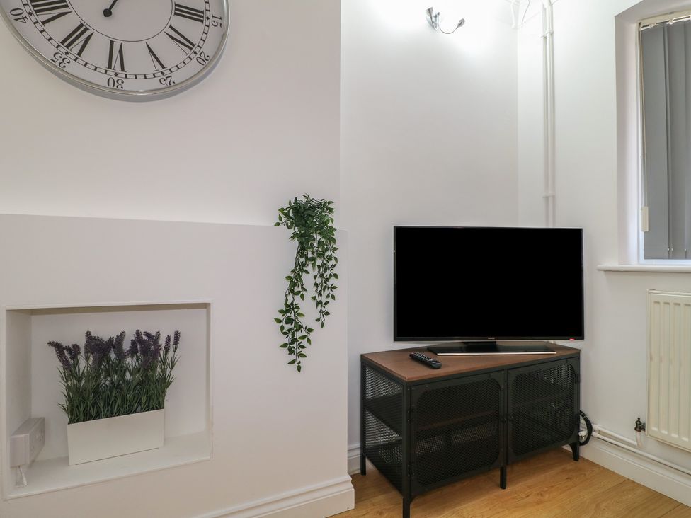 A living room with a clock and television at 12 Gorse Lane Syston