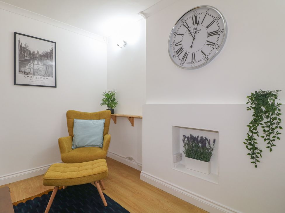 A living room with a chair, clock and plants at 12 Gorse Lane, Syston