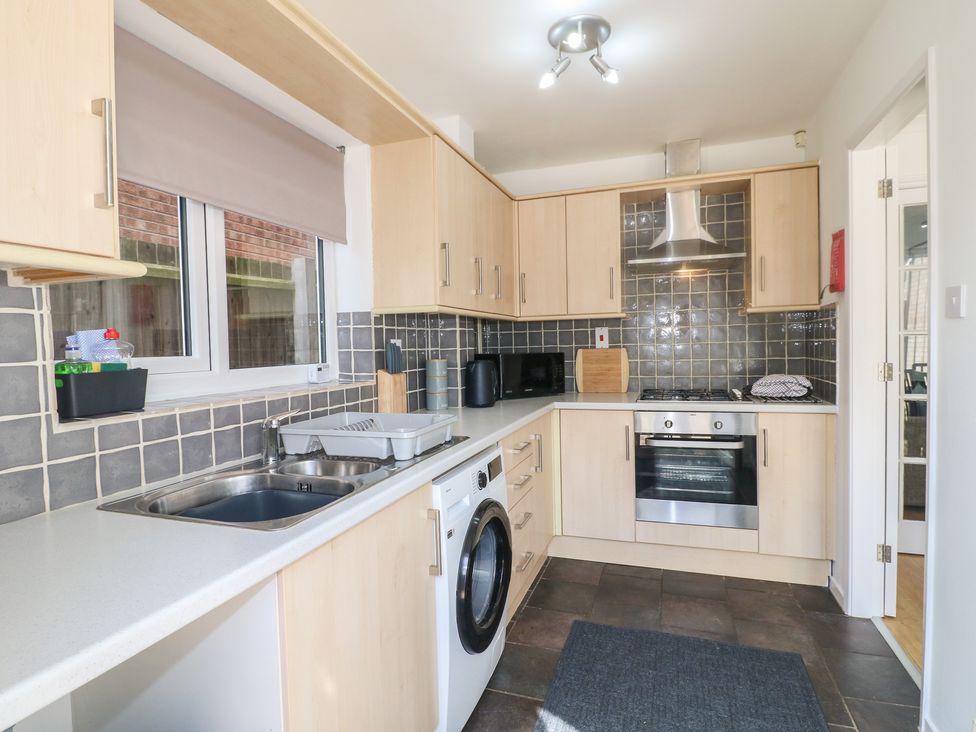 A kitchen with cabinets, sink, washing machine and oven at 12 Gorse Lane Syston