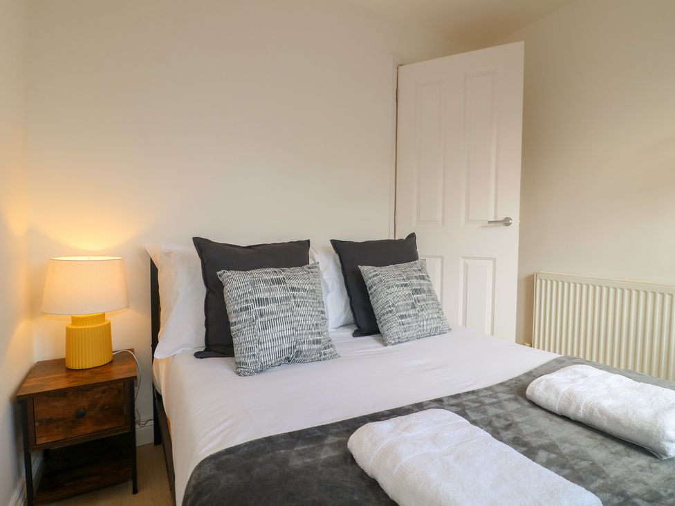 A bedroom with a bed and nightstand at 12 Gorse Lane in Syston