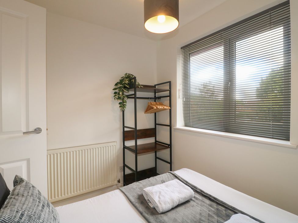 A bedroom with a bed and shelves at 12 Gorse Lane Syston