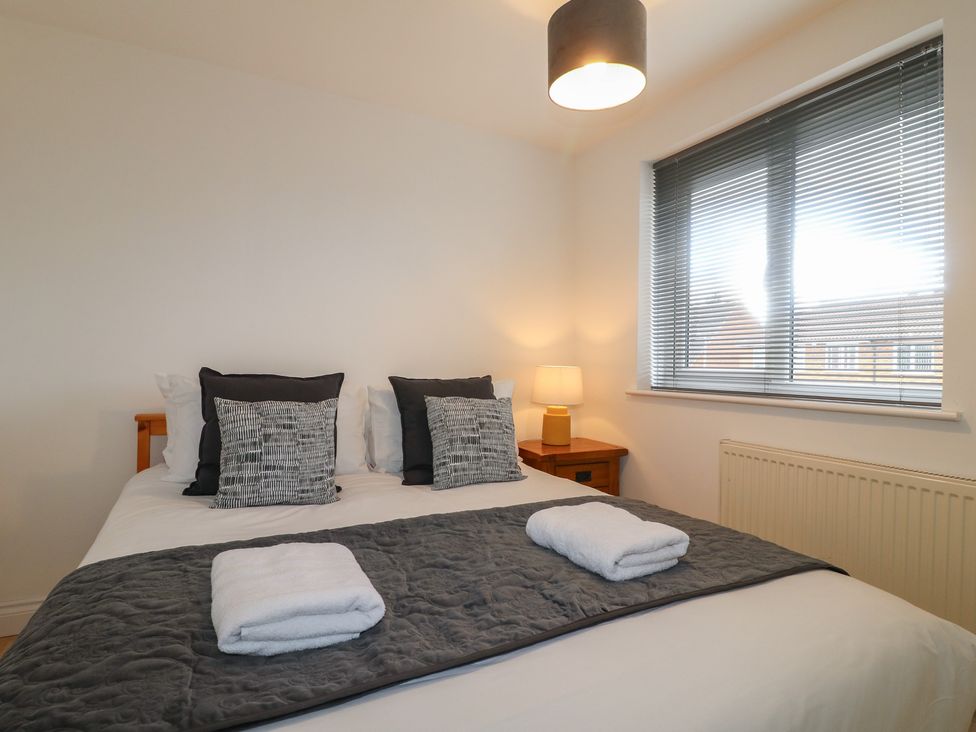 A bedroom with a bed, pillows, lamp and window at 12 Gorse Lane Syston