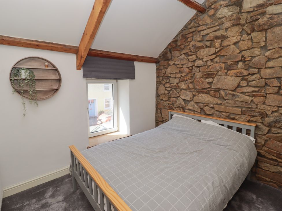 A bedroom with a bed and stone wall at 41 St. James Street in Narberth