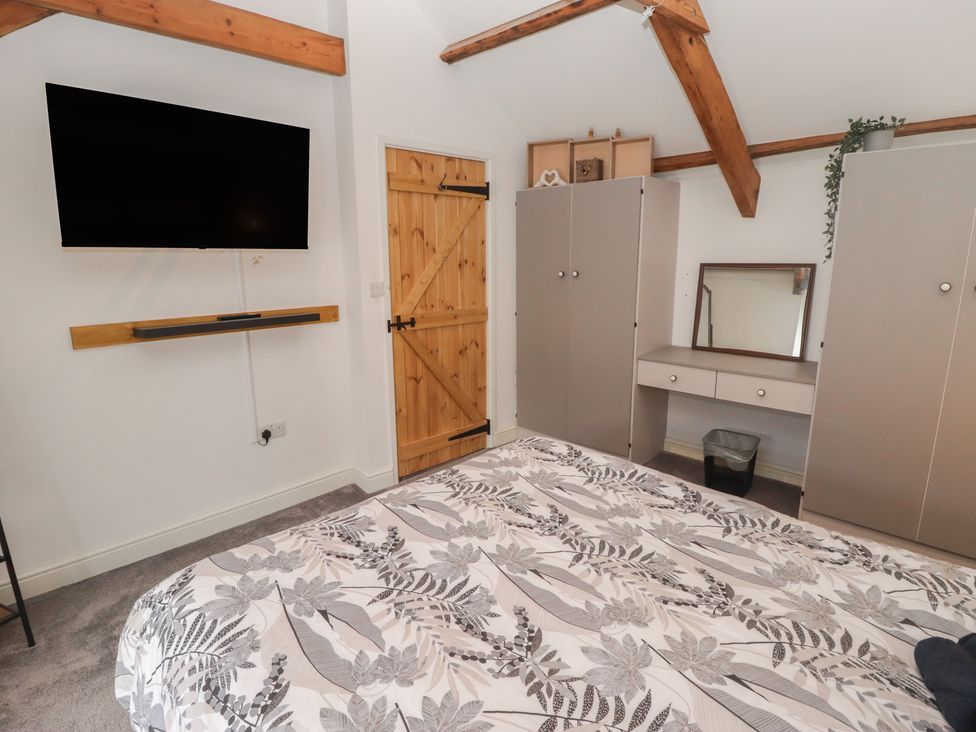 A bedroom with a bed, wardrobe, mirror, and television at 41 St. James Street, Narberth