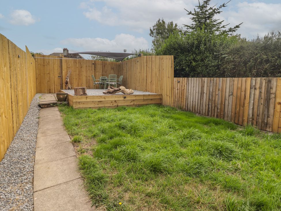 A garden with grass, a patio, chairs, and a table at 41 St. James Street Narberth