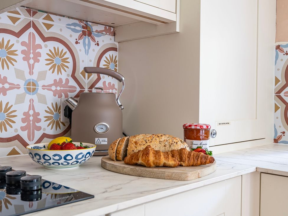 A kitchen with a kettle, bread, and strawberries at Bodior Lodge in Rhoscolyn