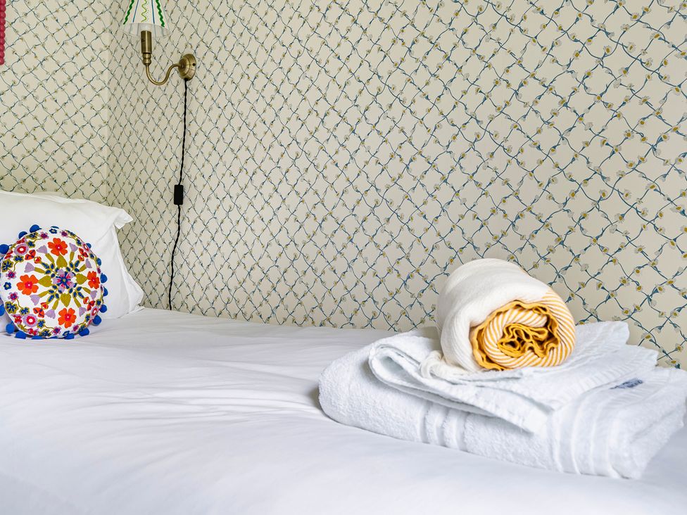 A bedroom with a bed, decorative cushion, and towels at Bodior Lodge in Rhoscolyn