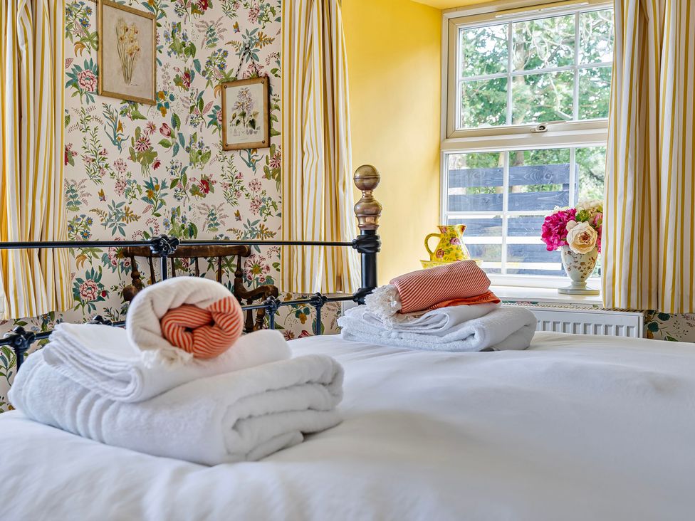A bedroom with bed, towels, and a window at Bodior Lodge Rhoscolyn