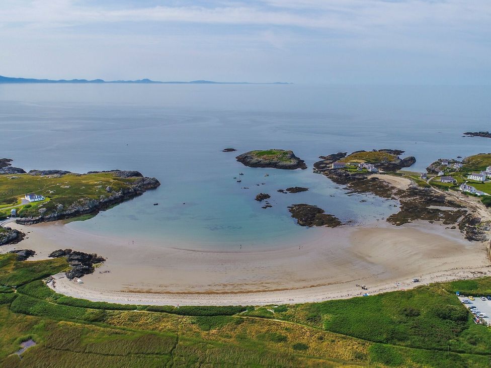 A beach with calm waters and scattered rocks at Bodior Garden Cottage in Rhoscolyn