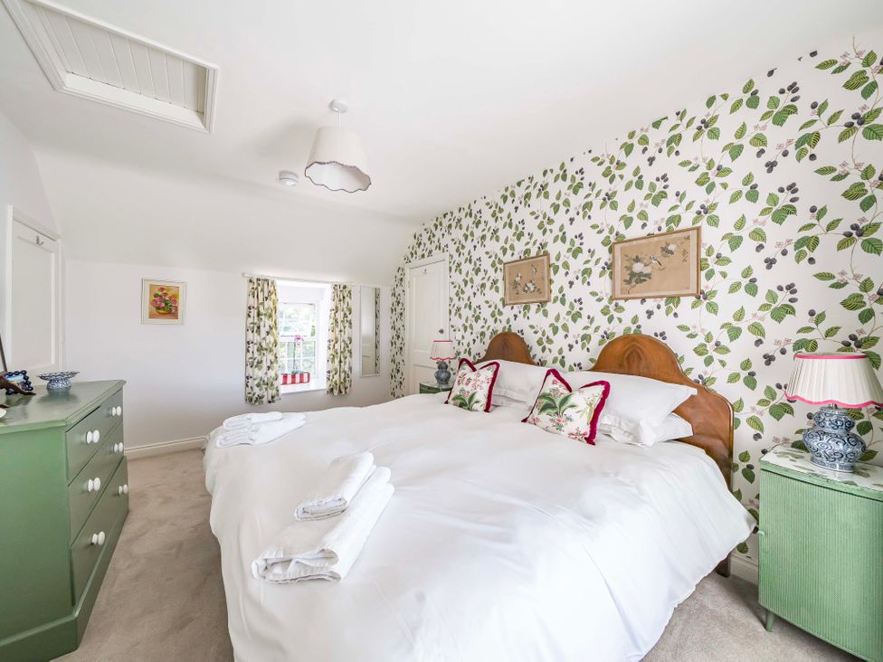 A bedroom with a double bed and green chest of drawers at Bodior Garden Cottage in Rhoscolyn