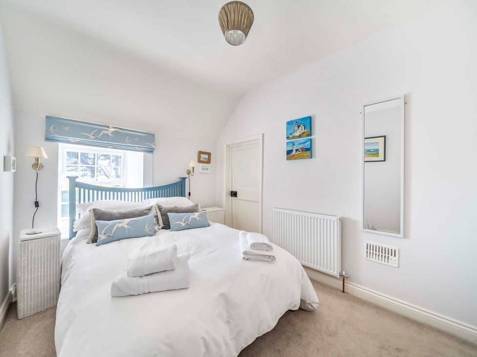 A bedroom with a bed and a window at Bodior Garden Cottage in Rhoscolyn