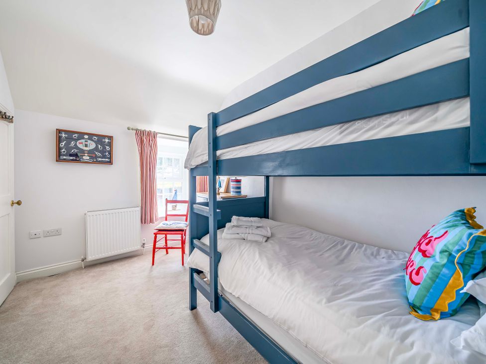A bedroom with a bunk bed and chair at Bodior Garden Cottage Rhoscolyn