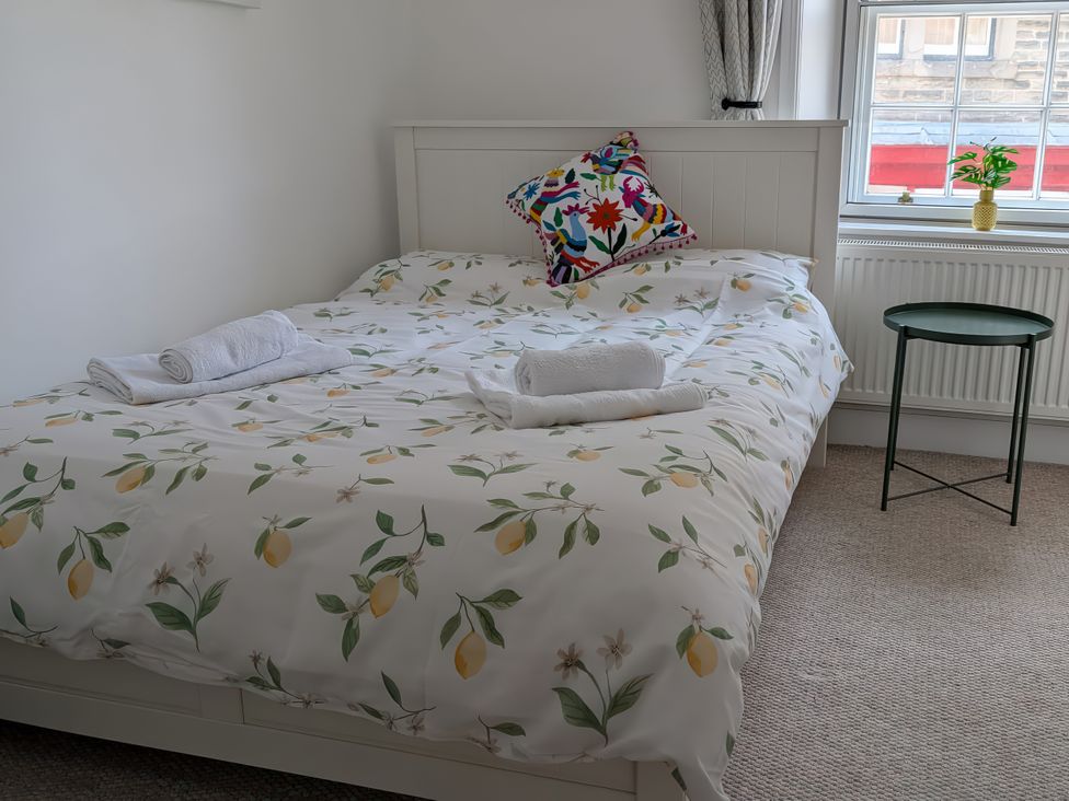 A bedroom with a bed and side table at 1A Market Street Buxton