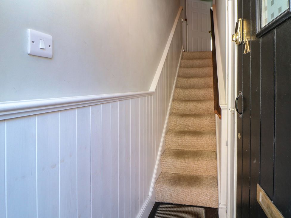 A staircase with a handrail and a black door at Cosy Cottage Buxton