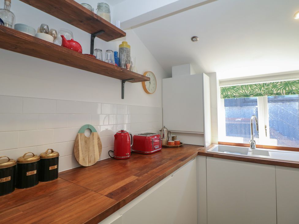 A kitchen with wooden shelves and a red kettle at Cosy Cottage in Buxton