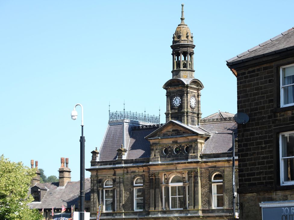 A clock tower on a historic building with windows and a lamp post at Cosy Cottage in Buxton