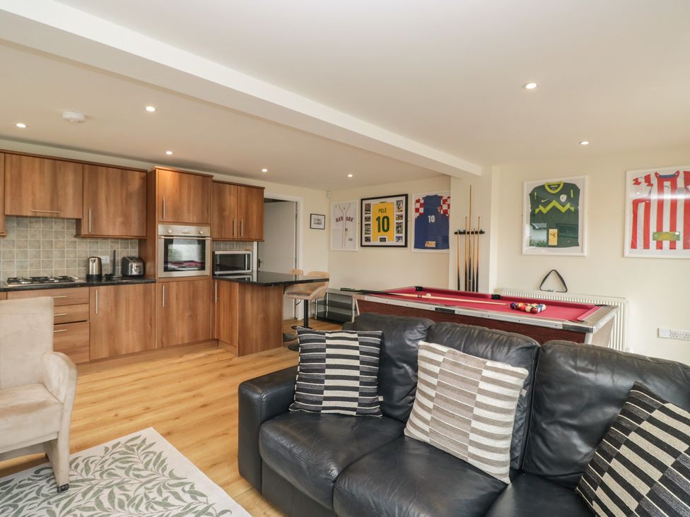 A living room with a pool table and kitchen units at Whimhowe Windermere