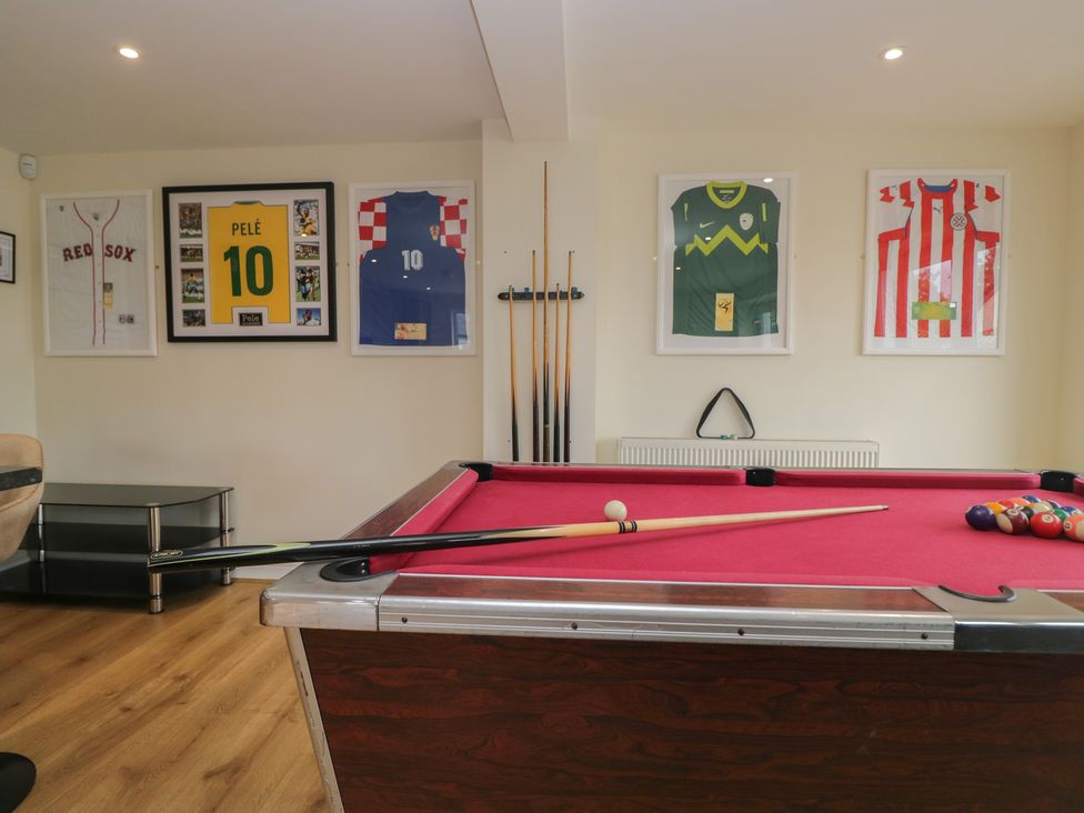 A games room with a pool table and framed sports jerseys at Whimhowe in Windermere