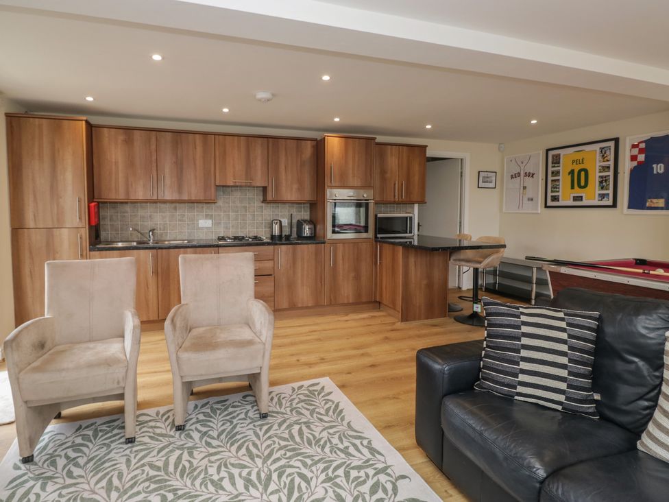 A living room with kitchen cabinets and seating area at Whimhowe in Windermere