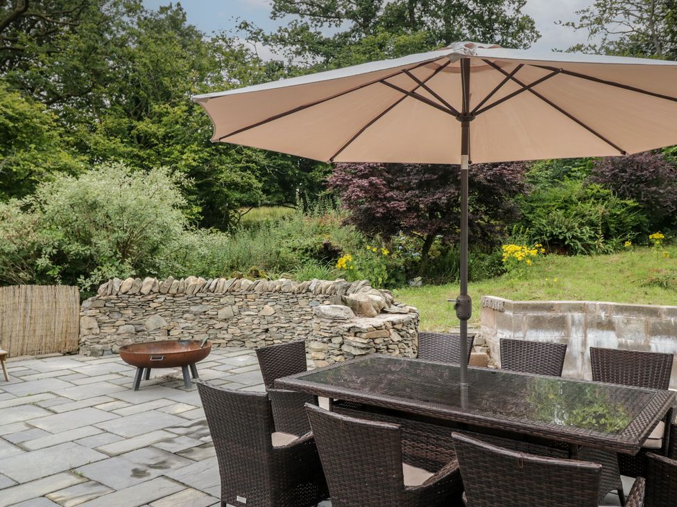 An outdoor dining table with chairs and an umbrella at Whimhowe in Windermere