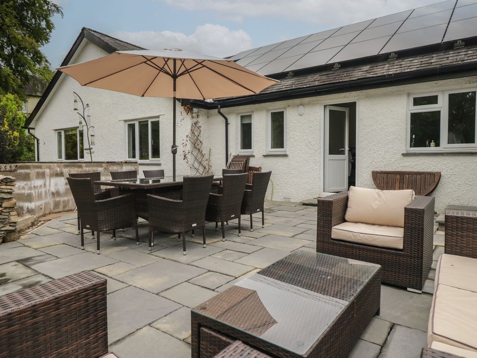 An outdoor patio with furniture and an umbrella at Whimhowe in Windermere