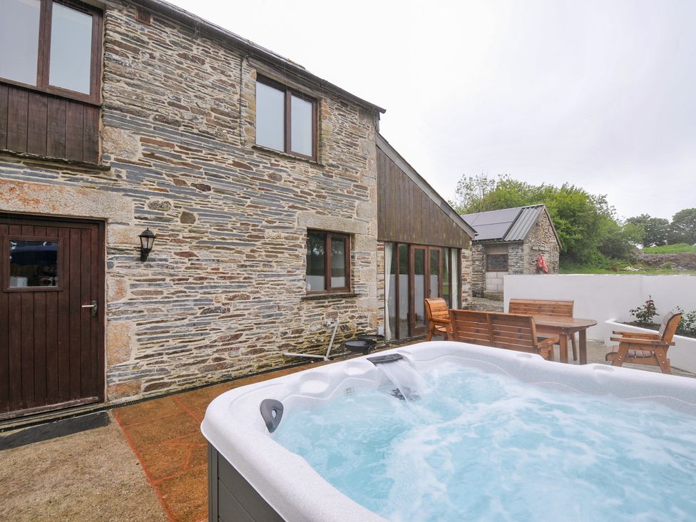 An outdoor area with a hot tub and seating at The Dairy Barn in Camelford