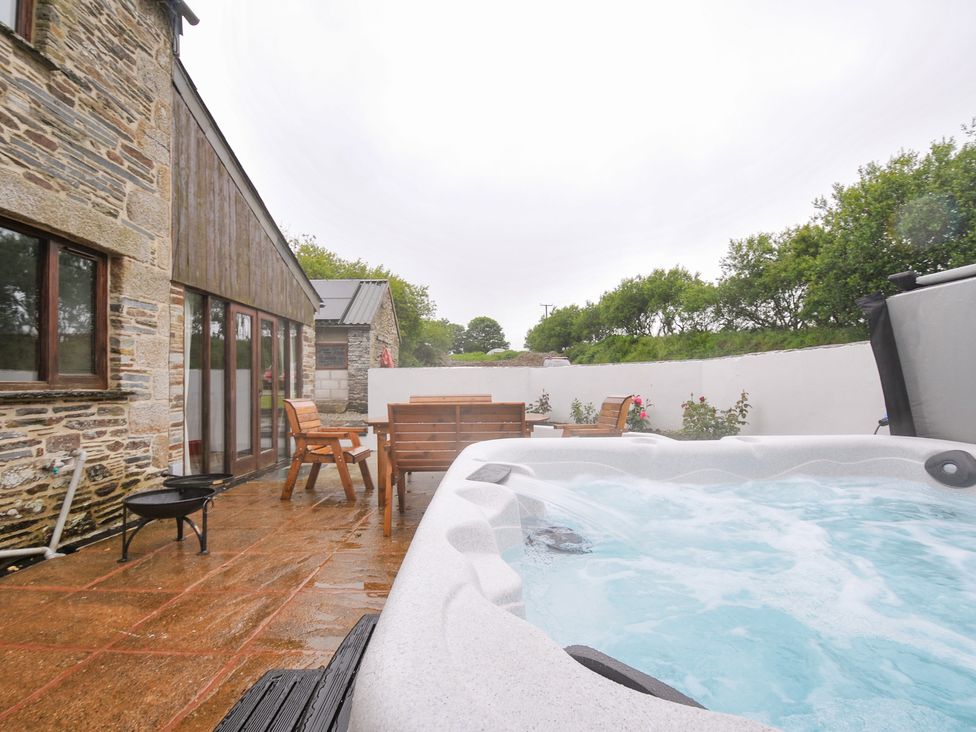 A garden with a hot tub and wooden furniture at The Dairy Barn in Camelford