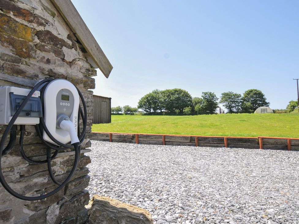 An electric vehicle charger on a gravel surface in an outdoor area at The Dairy Barn in Camelford