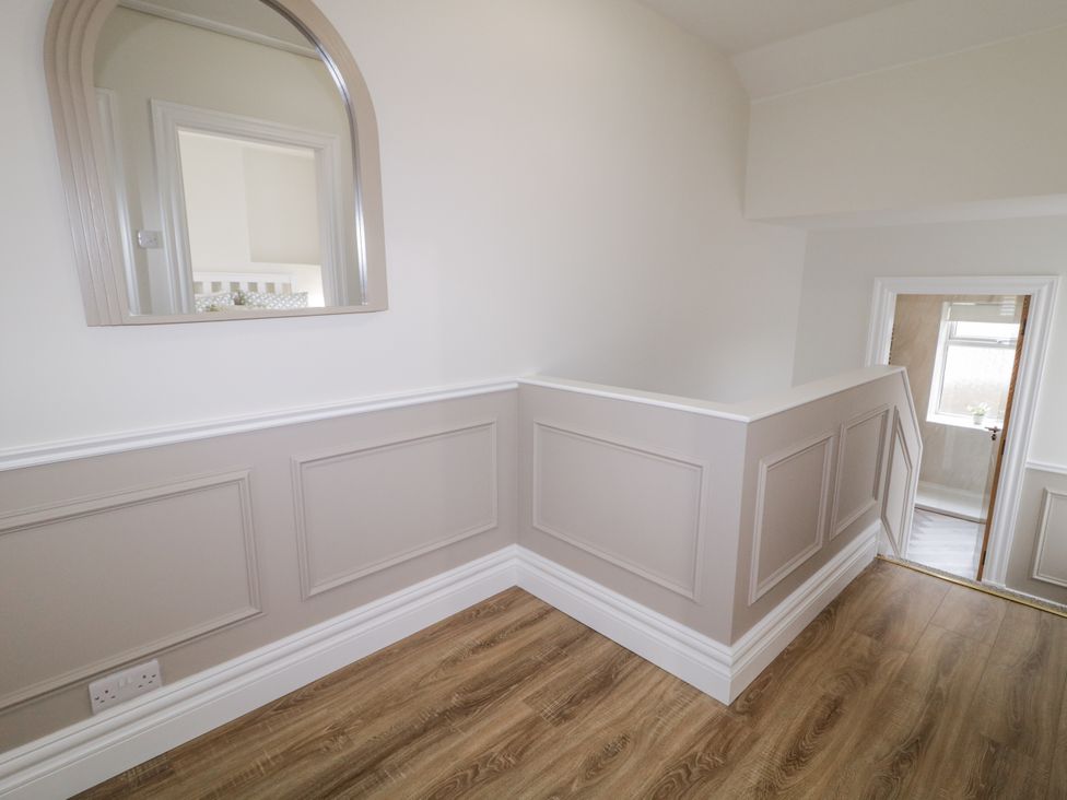 A hallway with a mirror and floor leading to a door at 41 Church view in Portstewart