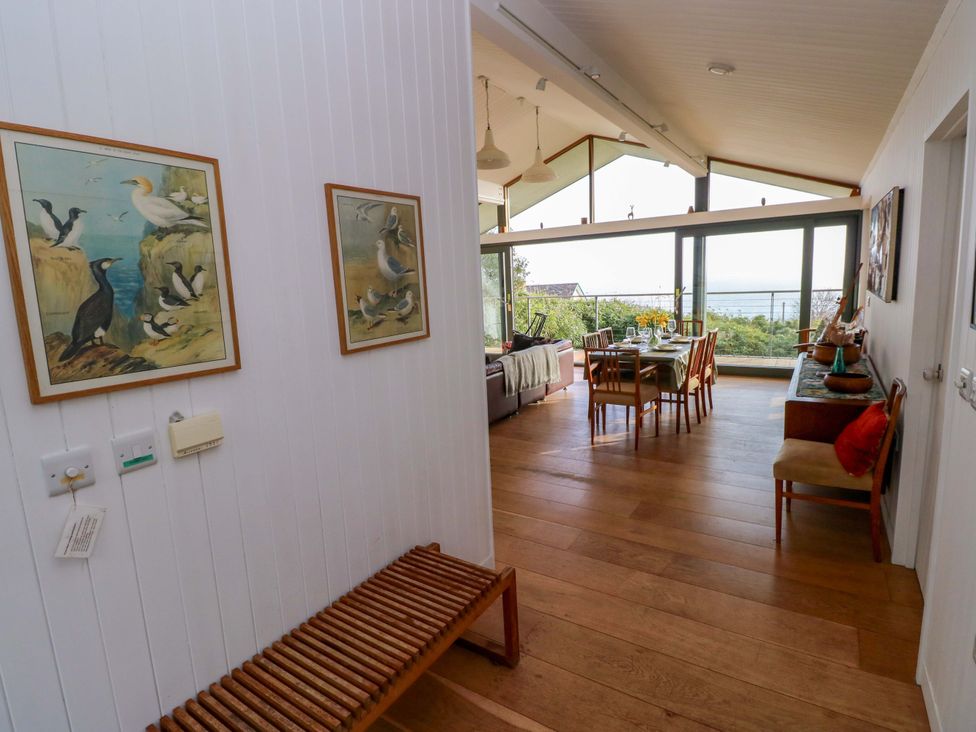 A living room with a dining table and paintings at Green Shutters near Freshwater East