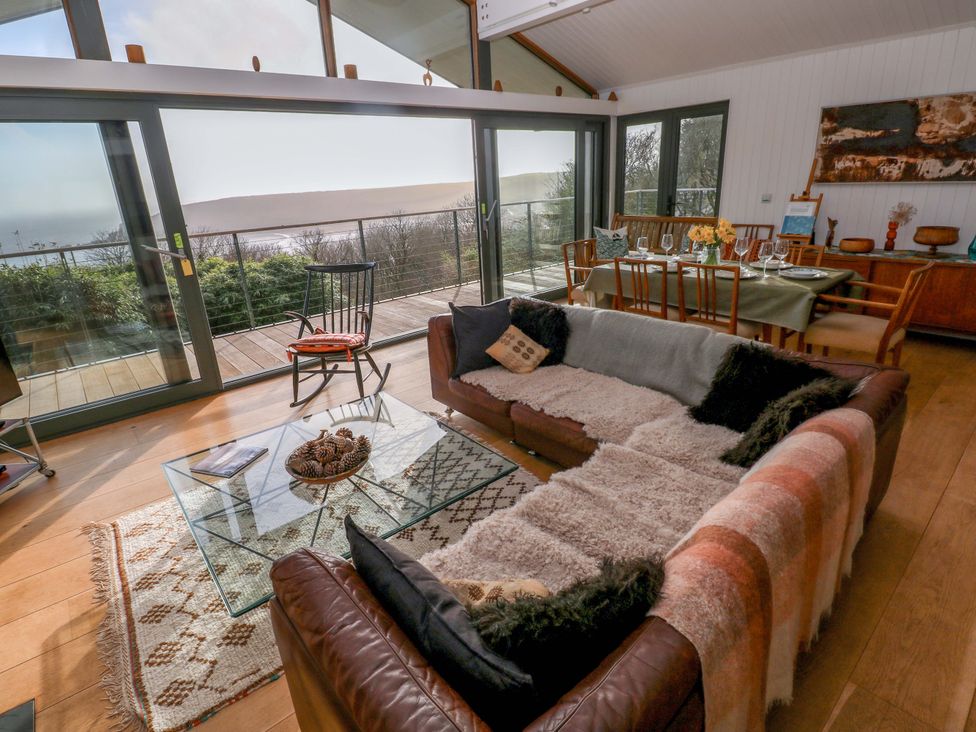 A living room with a sofa and dining area at Green Shutters in Freshwater East near Lamphey