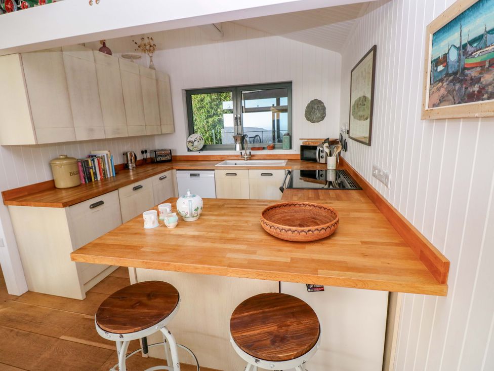 A kitchen with a sink, stove and bar stools at Green Shutters Freshwater East near Lamphey