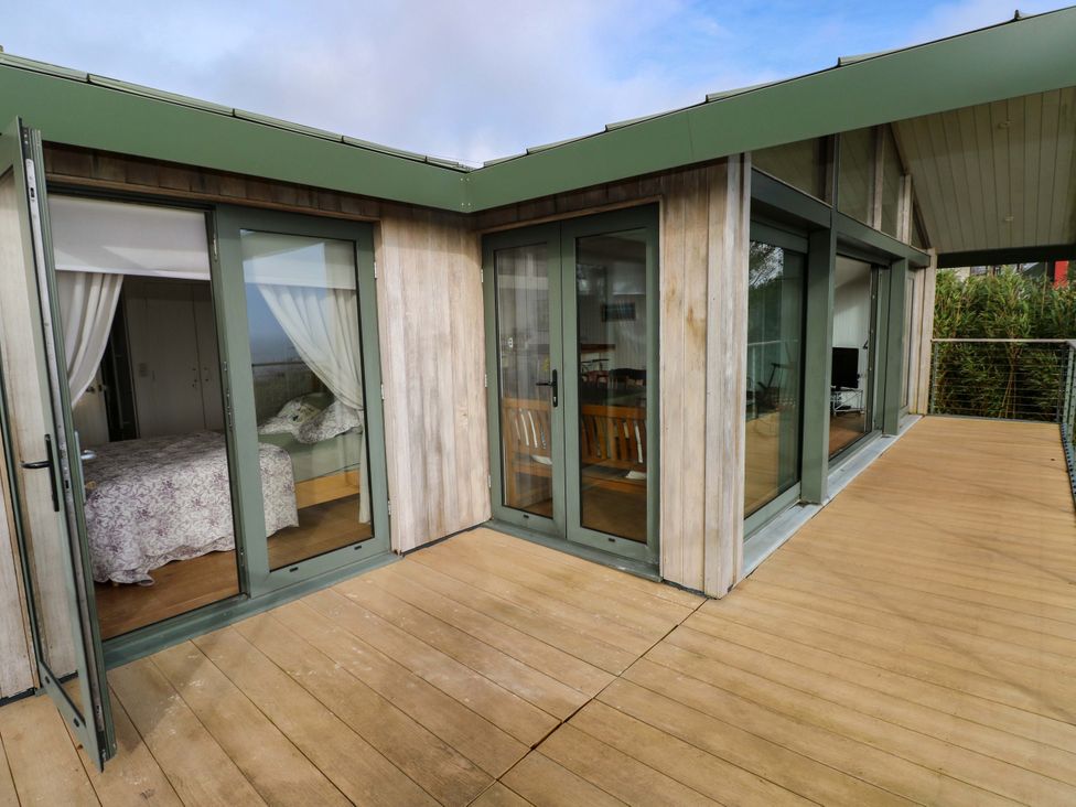 An outdoor deck area with glass doors leading to a bedroom at Green Shutters Freshwater East near Lamphey