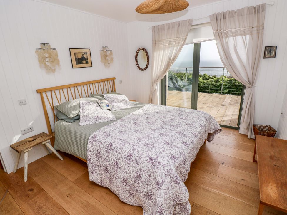 A bedroom with a bed and large window at Green Shutters in Freshwater East near Lamphey