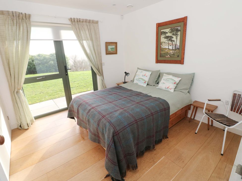 A bedroom with a bed and a chair at Green Shutters in Freshwater East near Lamphey