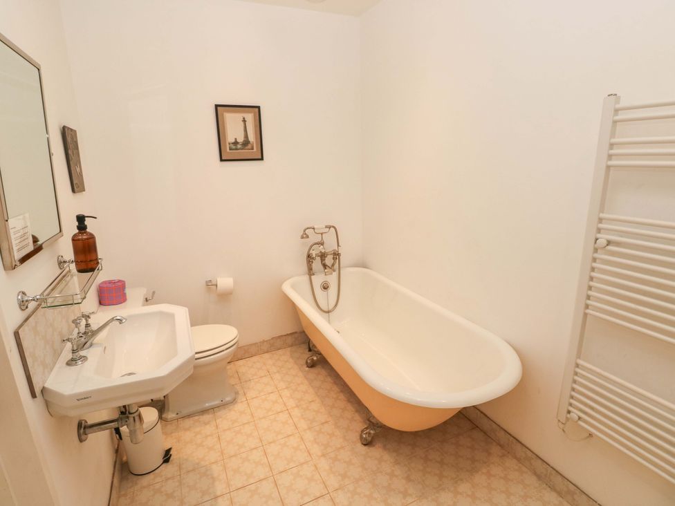 A bathroom with a bathtub, sink, toilet, and towel radiator at Green Shutters, Freshwater East near Lamphey