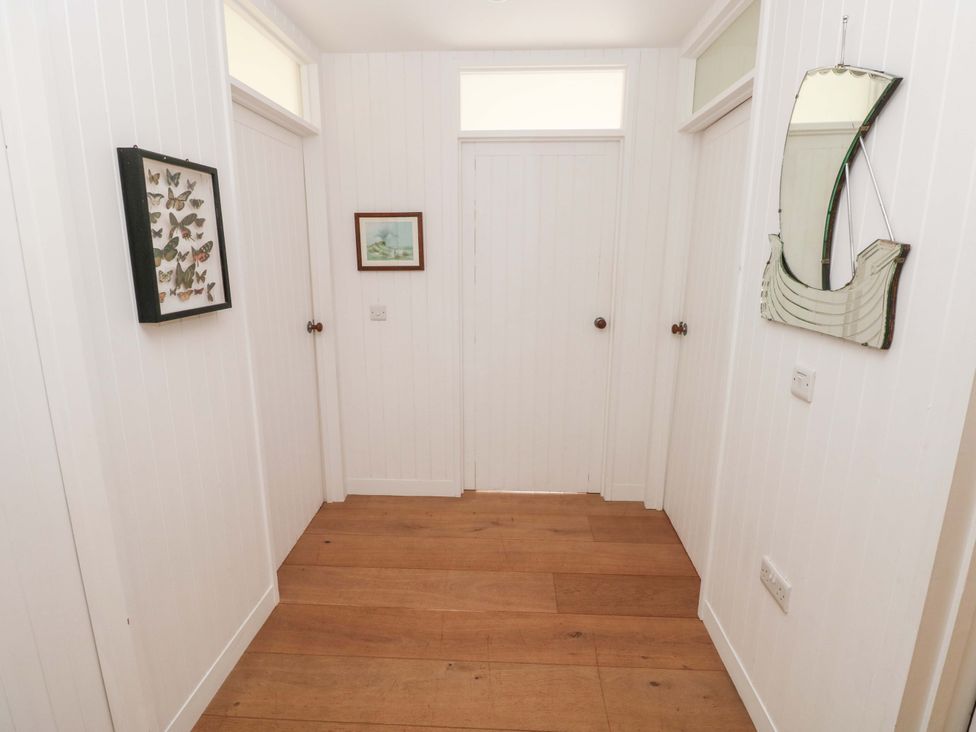 A hallway with butterfly frame and paintings at Green Shutters Freshwater East near Lamphey