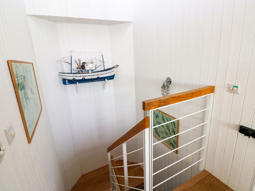 A stairwell with a model boat and framed pictures at Green Shutters Freshwater East near Lamphey