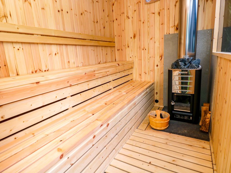 A sauna with wooden benches and a stove at Green Shutters Freshwater East near Lamphey