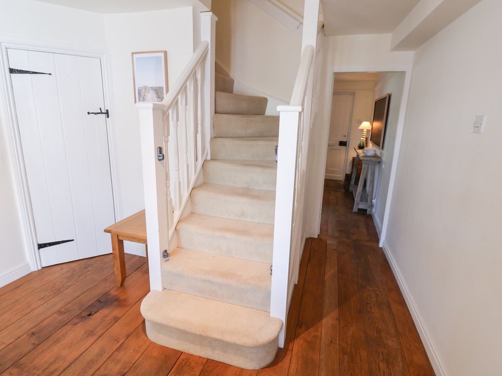 A hallway with a staircase and a table at Victoria Cottage (4 East Green) Southwold