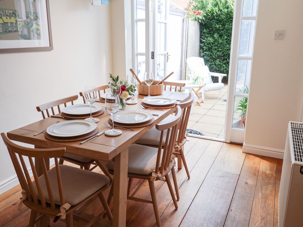 A dining room with a table set for a meal at Victoria Cottage (4 East Green) Southwold