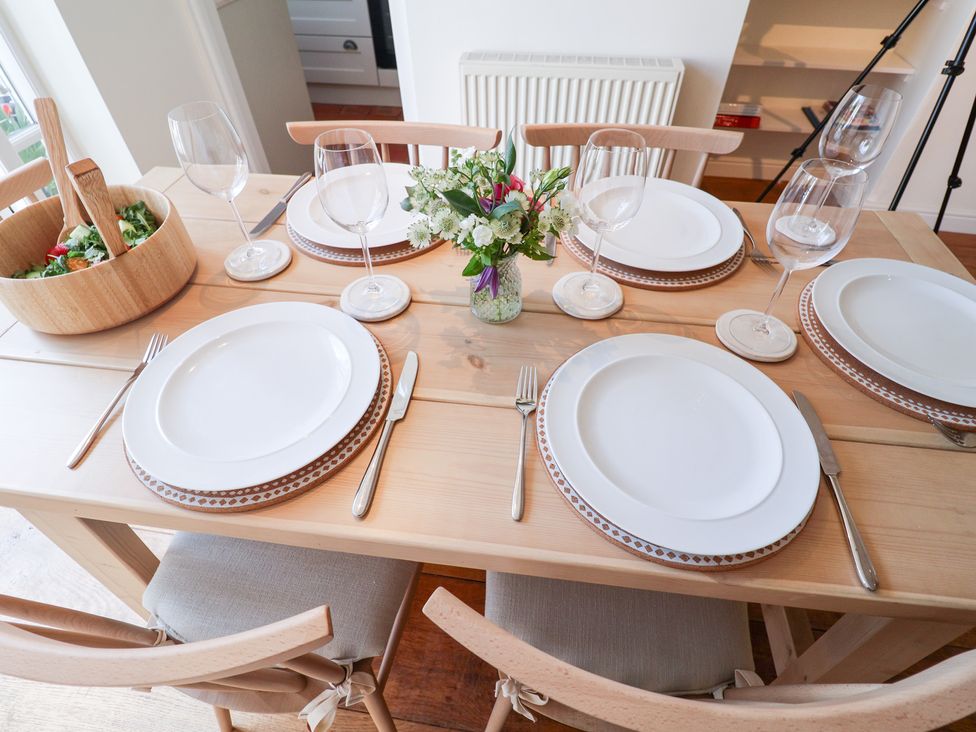 A dining table set with plates and wine glasses at Victoria Cottage (4 East Green) Southwold