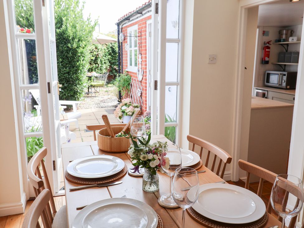 A dining room with a table set for meals at Victoria Cottage (4 East Green) Southwold
